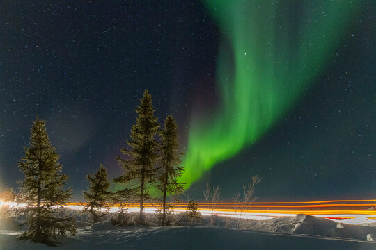 Long exposure of Jeep lights and Aurora Borealis over Great Slave Lake at night in Northwest Territories Canada