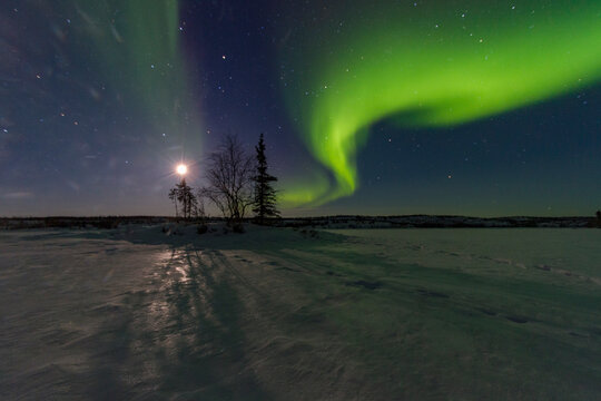 Northern lights shine over boreal forest and Great Slave Lake in Canada at night