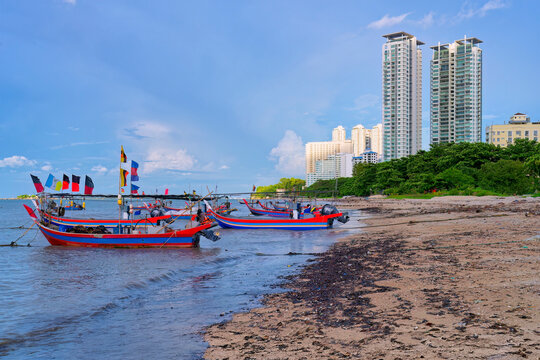 Fishing boats near city skyline along the Malacca Strait close to the Penang Floating Mosque in Penang, Malaysia during daytime