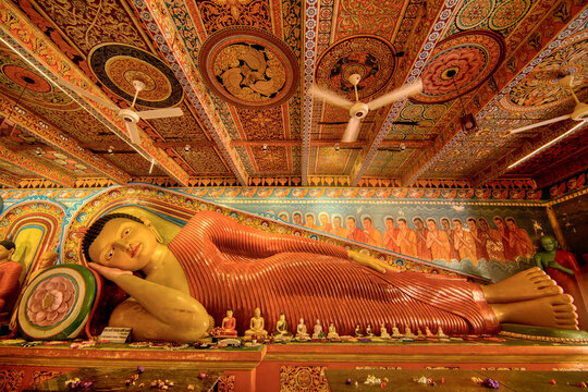 A reclining Buddha statue shows intricate details and designs within Isurumuniya Rajamaha Viharaya temple