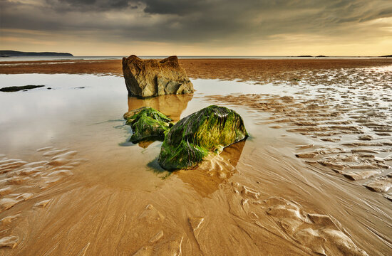 Low tide view of rocks, rippled sand and water pools on the beach in Bigbury-on-Sea, Devon, Great Britain