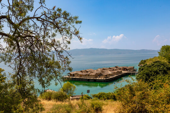 Stilted village of thatched huts over turquoise water with mountains in the distance