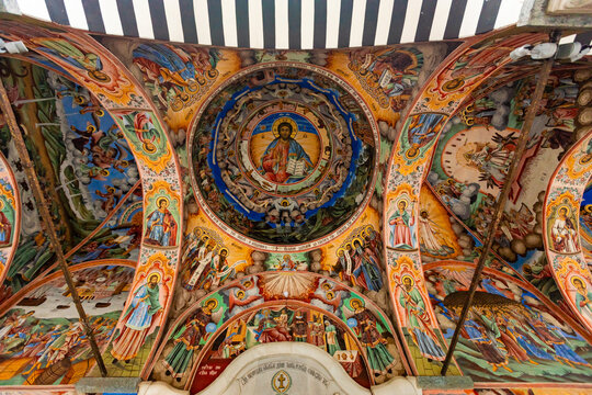 Detailed frescoes adorn the ceiling in the portico of the main church at Rila Monastery in Bulgaria showcasing religious themes and figures