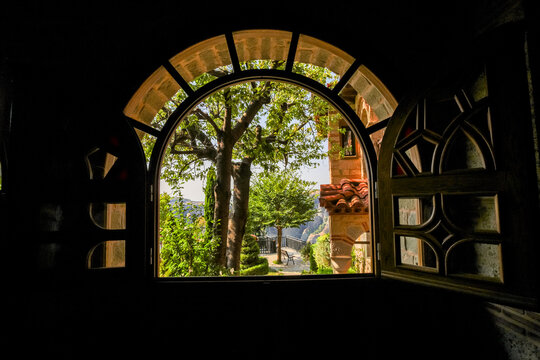 Scenic view of courtyard and mountains through an arched window in Meteora, Thessaly, Greece