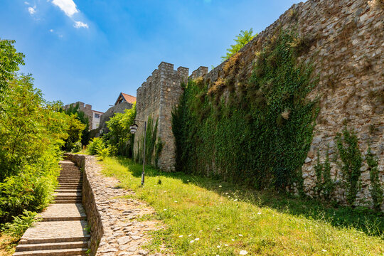 Cobblestone path and steps beside an ivy wall at a monastery near Lake Ohrid under midday sky