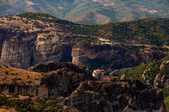 Meteora monasteries on rock pillars with rugged cliffs and green hills in Thessaly, Greece