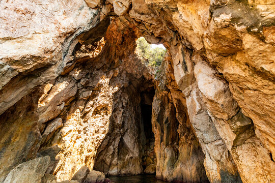 Exploring a rock arch and sea cave with sunlight shining on the stone walls near Dhermi in Albania