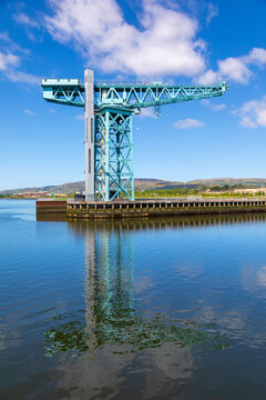 Clydebank Titan crane stands tall beside River Clyde with reflection in the water on a bright sunny day