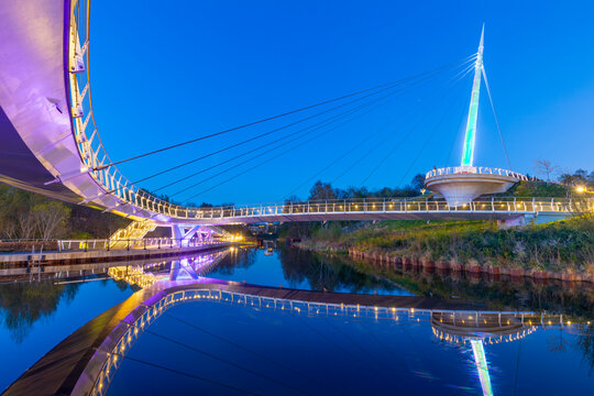 Stockingfield Bridge reflects in the waters of the Forth and Clyde Canal during twilight in Glasgow, Scotland