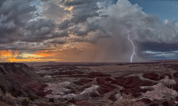 Dark clouds gather over Kachina Point as a storm approaches Petrified Forest National Park during sunset in Arizona