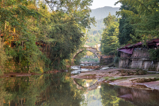 Famous ancient arch stone bridge in Shangli Town at sunrise with reflections in the water