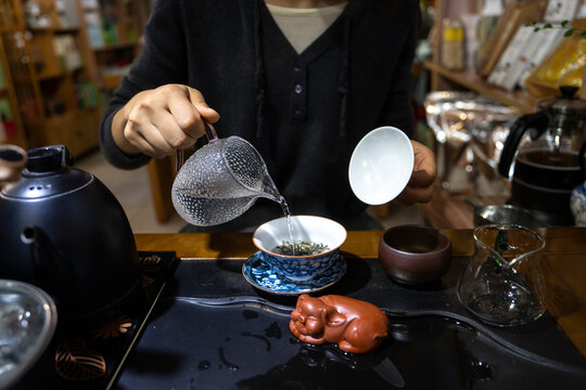 Woman pours tea into a cup during a tea ceremony in Sichuan, China, showcasing traditional practices at Shangli