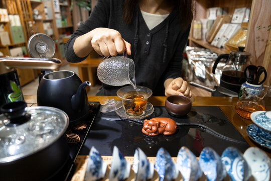 Woman pours tea into a glass during a ceremony in a traditional setting in Sichuan, China
