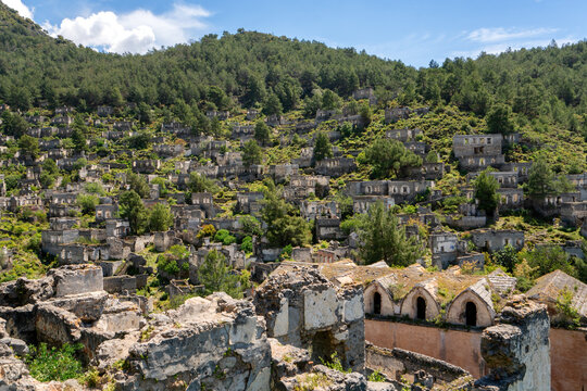 Exploring the abandoned houses and church of Kayakoy ghost town in Fethiye Turkey surrounded by mountains and vegetation