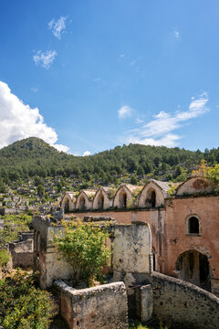 Exploring the ruins of Kayakoy Greek ghost town with mountains and vegetation in the background in Fethiye Turkey