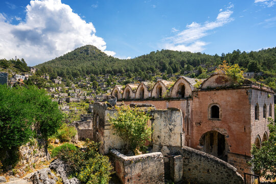 Exploring the abandoned houses and church in Kayakoy ghost town surrounded by mountains and vegetation in Fethiye, Turkey