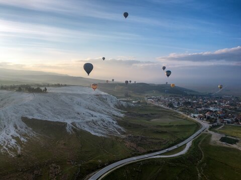 Hot air balloons float over Pamukkale at sunrise in Turkey