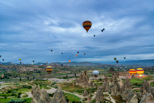 Hot air balloons rise in Cappadocia as the sun begins to light the sky over the valleys and rock formations