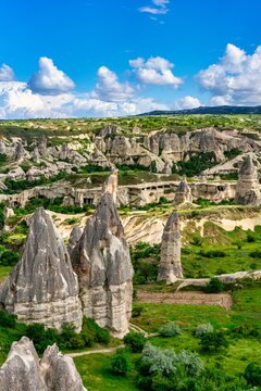 View of unique rock formations in Rocket Valley in Cappadocia with clear sky and green landscape during daytime