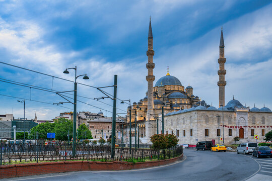 Yeni mosque stands illuminated at sunset in Istanbul, Turkey as day turns to night over the landscape and city