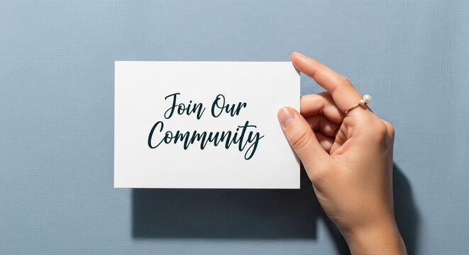 Hand holding white card with the inscription "Join Our Community", gold ring, light blue textured surface, symbolizing invitation and relationship