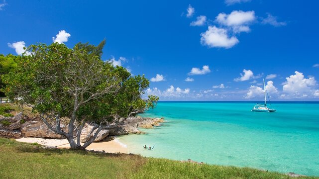Catamaran sails past a sandy beach in Drews Bay on the east end of Bermuda