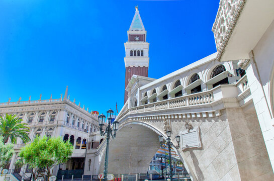 View of a tall clock tower and bridge under a clear blue sky with buildings in the background