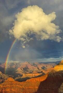 Rainbow appears over the Grand Canyon during afternoon with clouds in the sky
