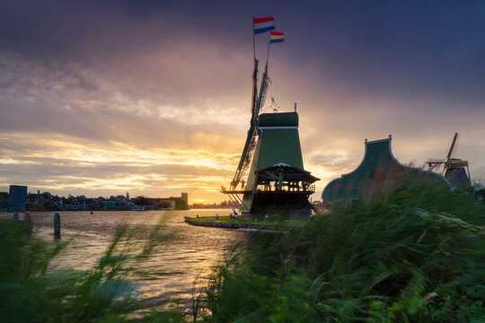 Windmill at sunset in summer with flags in Zaanse Schans, North Holland, Netherlands