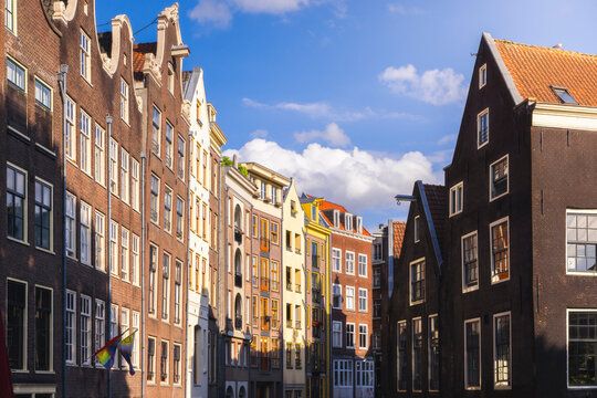 Houses in Amsterdam catch the warm light of sunset over North Holland skies in Western Europe