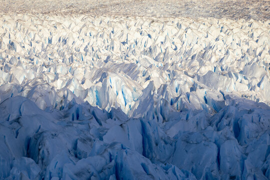 Massive glacier front of Perito Moreno reveals blue ice formations and rugged terrain in Patagonia Argentina