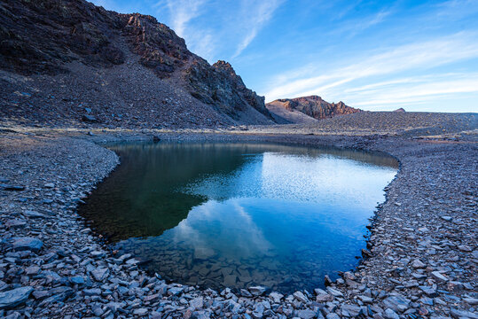 Clear mountain reflections in a high alpine tarn near Cerro del Caballo in Sierra Nevada National Park, Andalusia, Spain