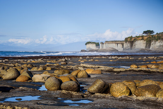 Boulders along the intertidal zone with limestone cliffs and Tasman Sea view in New Zealand's west coast