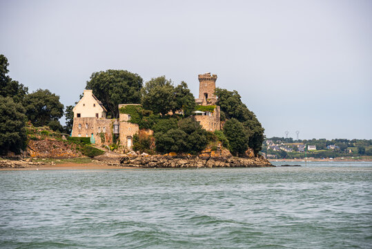 Chateau de Phou stands tall on a wooded peninsula in Rance estuary surrounded by water in Brittany, France
