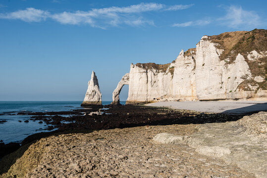 View of the chalk cliffs and sea stack at Etretat in Normandy on a clear day with blue skies above