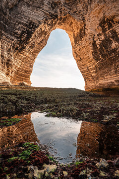 View of chalk cliff arch with mirror reflection in tidal pool at low tide in Etretat France