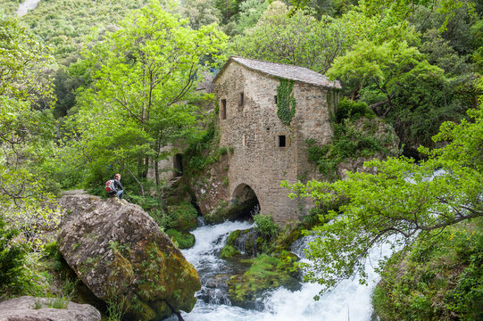 Exploring the ancient water mill in the Gorges of the Vis River surrounded by lush green trees and flowing water in southern France