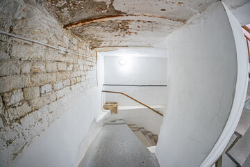 Ancient castle interior, decaying stairwell, peeling paint, rusted pipes, water damage, curved ceiling, darkness, worn steps, dusty railing, perspective from above, dim lighting, long shadows, time p © Mister