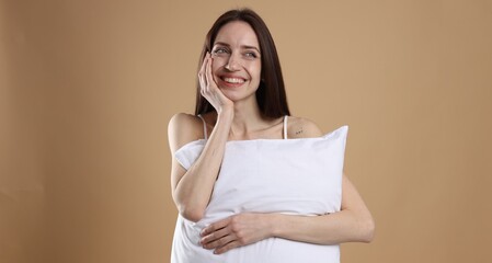 Fototapeta premium Beautiful woman with pillow on beige background