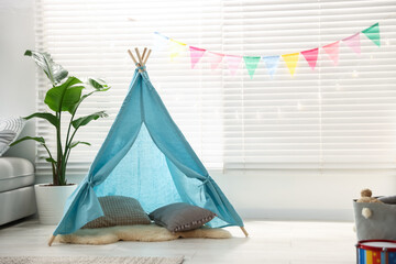 Child's room with toy wigwam, colorful flags and decorative lights. Interior design © New Africa