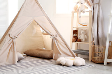 Stylish toy wigwam, furniture, pillows and decor in light playroom. Interior design © New Africa