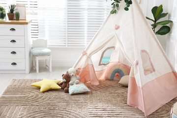 Toy wigwam with pillows, furniture and floral decor in room © New Africa