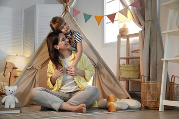 Mother and her daughter near toy wigwam at home © New Africa