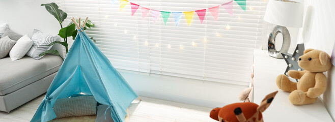 Child's room with toy wigwam, toys, colorful flags and decorative lights. Interior design © New Africa