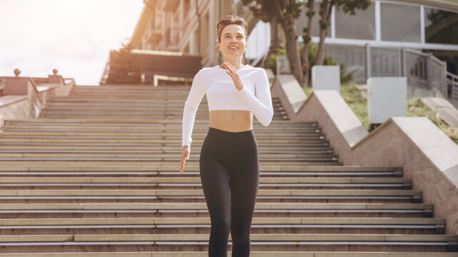 Young woman running up urban stairs, feeling active and energetic in a fitness workout, promoting a healthy lifestyle