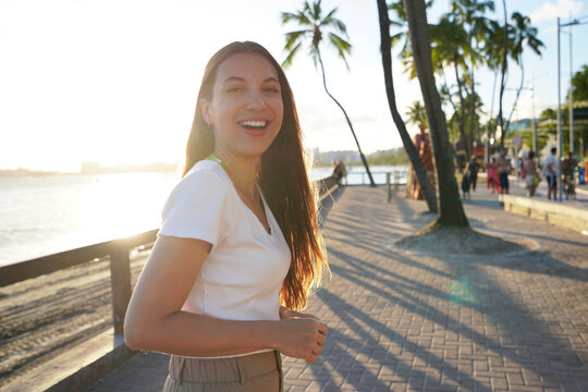 Cheerful laughing woman walking on Maceio city promenade at sunset, Brazil