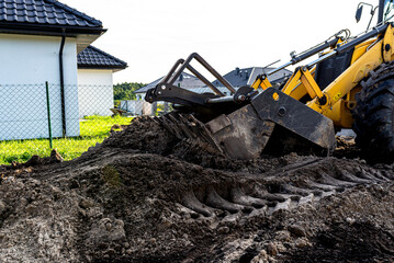 Fototapeta premium Backhoe loader bucket moving soil on construction site