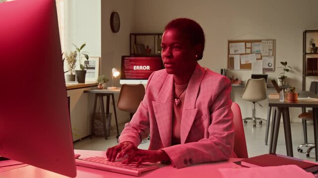 Zoom in view of African American young woman panicking and frantically typing on keyboard trying to fix system error while working on computer in office setting