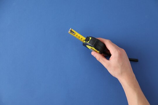 Man with measuring tape on blue background, top view. Space for text
