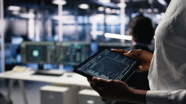 Close up of data center programmer using tablet, writing code for resource optimization, performing updates. Server room employee using device, compiling software patches to fix bugs, camera A
